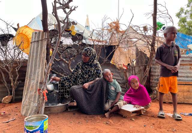En mamma i Somalia lagar mat åt sina tre barn i ett flyktingläger för internflyktingar.
